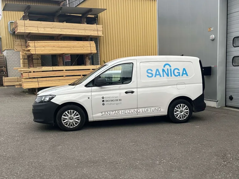 Weisser Servicewagen der Saniga AG mit der Beschriftung Sanitär Heizung Lüftung vor einer Lagerhalle