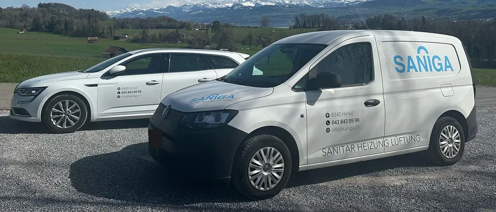 Lieferwagen und Kombi der Saniga AG mit Firmenbeschriftung vor einem Alpenpanorama